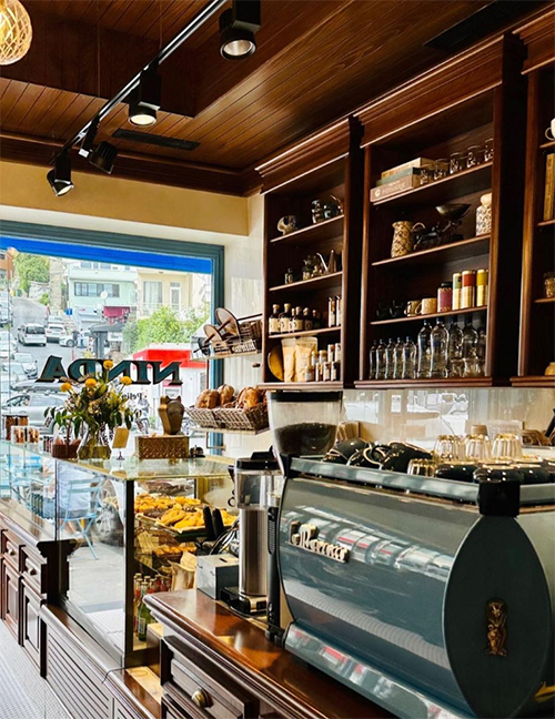 Ninda kafenin retro tasarımlı iç mekanında, parlak ahşap tavan ve rafların altında, taze kruvasanlar ve tatlılarla dolu cam vitrin ile modern bir kahve makinesi, dışarıdaki Bebek caddesi manzarası eşliğinde şehrin en iyi kahve ve tatlı duraklarından birini yansıtıyor.
