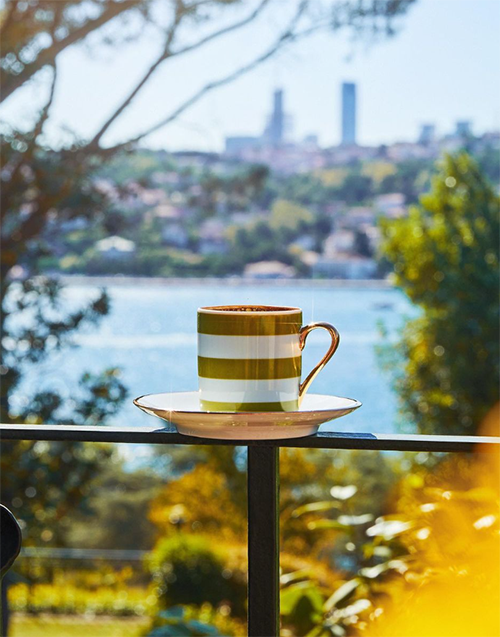 Bebek'in seçkin mekanlarından Selamlıque'nin sunduğu, Boğaz'ın göz alıcı manzarasına karşı duran korkuluk üzerinde, beyaz ve zeytin yeşili çizgili zarif bir fincanda, köpüklü bir kahve keyfi yaşanırken, uzak şehir silüeti ve yeşil tepeler güneşte parlıyor.