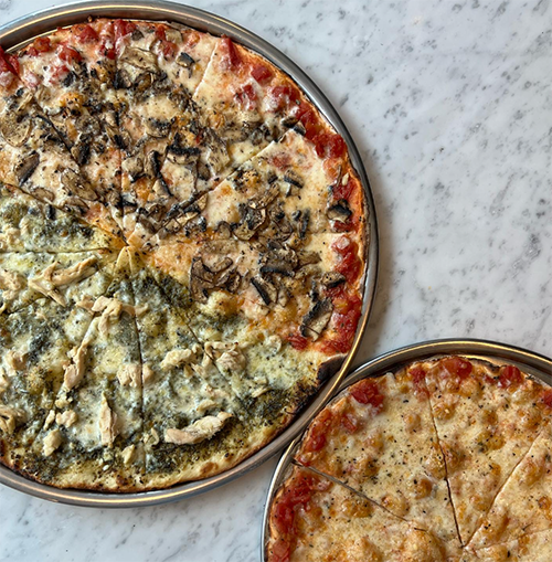 Bebek'in en iyi mekanlarından The Upper Crust Pizzeria'nın sunduğu, dört farklı çeşitteki dilimleriyle dikkat çeken mantarlı, pesto soslu tavuklu, bol peynirli ve domates soslu gurme pizza ile klasik baharatlı bir başka pizzanın mermer yüzeyde iştah açıcı sunumu.