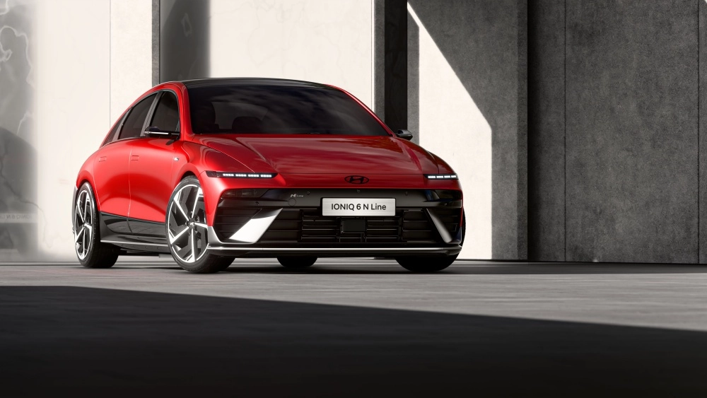 Parlak kırmızı renkli, şık dış tasarıma sahip yeni Hyundai IONIQ 6 N Line elektrikli otomobil, modern bir stüdyo ortamında ön cepheden ve yandan kısmen görünecek şekilde park edilmiş, detaylı jantları ve aerodinamik çizgileriyle dikkat çekiyor.