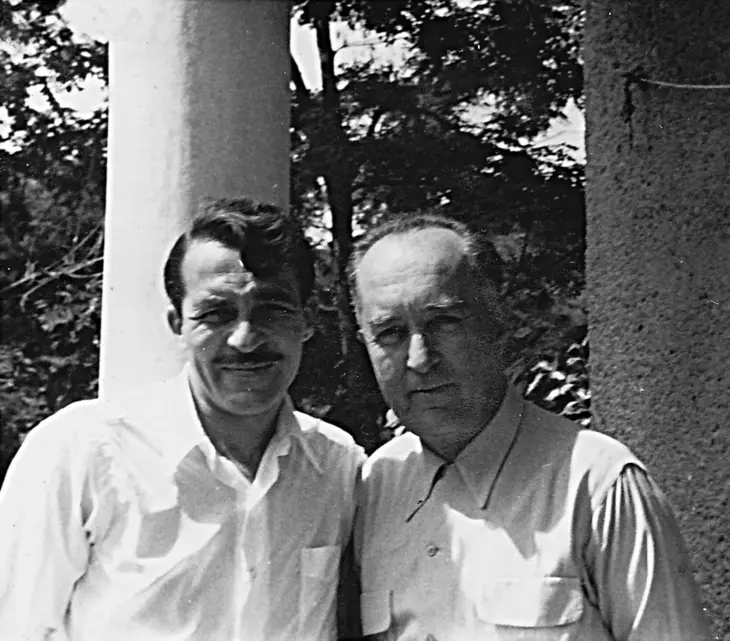 Siyah beyaz karede, Burhan Doğançay'ın gençlik yıllarından bir an olarak, bıyıklı ve açık renk bir gömlek giymiş sanatçı, yanında duran daha yaşlı bir beyle birlikte, ağaçlar ve sütunlar arasında samimi bir şekilde poz vererek hayatından bir kesit sunuyor.
