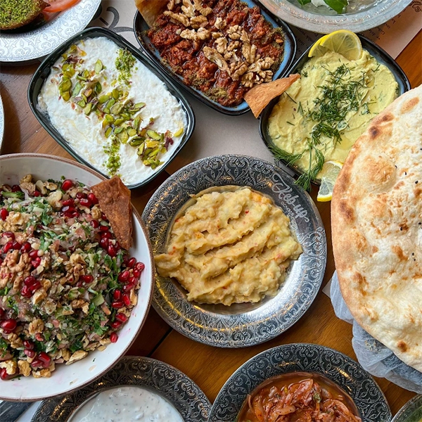Keb-up markalı tabakta servis edilen pürüzlü patates ezmesi, nar taneli ve cevizli bol yeşillikli salata, Antep fıstığı süslemeli yoğurtlu meze, cevizli acılı ezme ve dereotlu sarımsaklı humusun da bulunduğu zengin bir kebap sofrasından lezzet dolu çeşitli mezeler, İzmir'in en iyi restoranları arasında yer alan bir mekanda keyifli bir başlangıç sunuyor.