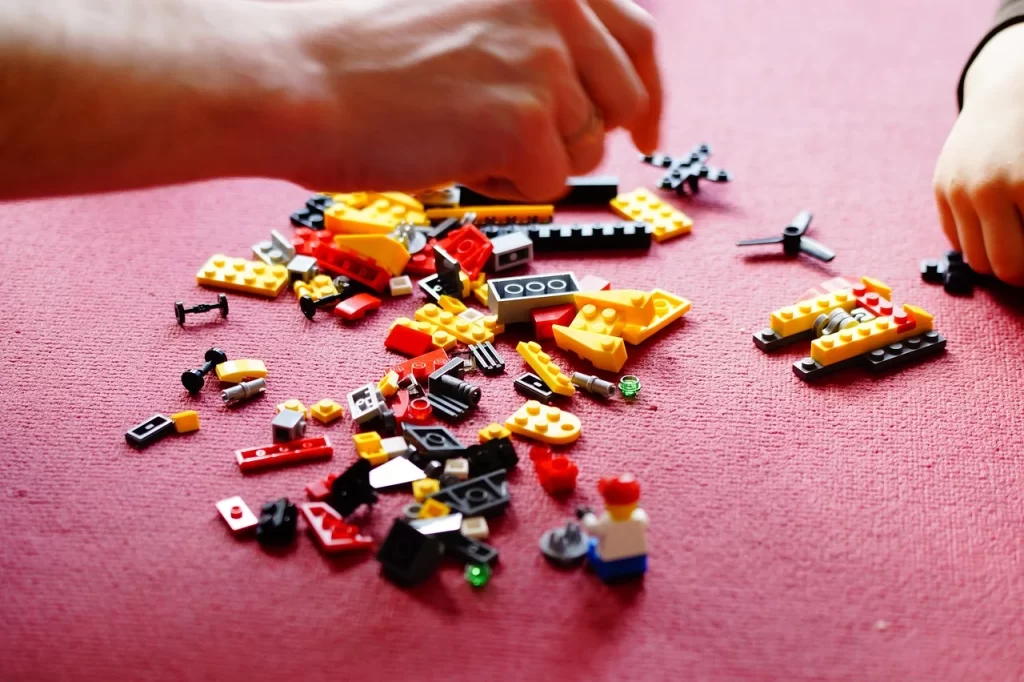 Mistik Güzelliğiyle Prag Seyahat Rehberi yazısında bahsedilen, hem çocukların hem de yetişkinlerin keyifli vakit geçirebileceği Lego Müzesi'ndeki interaktif oyun deneyimini yansıtan bu yakın çekim karede, kırmızı bir zemine yayılmış sarı, kırmızı ve siyah Lego parçalarıyla iki kişinin eli görülüyor.