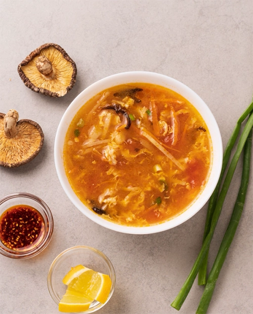 İzmir'in en iyi Uzak Doğu restoranlarından birinde sunulan, kurutulmuş shiitake mantarları, jülyen sebzeler ve çırpılmış yumurta ile zenginleştirilmiş, buğulu, kırmızımsı turuncu renkli bir çorba, yanında acı yağ, dilimlenmiş limon ve taze yeşil soğanlarla iştah açıcı bir şekilde servis ediliyor.