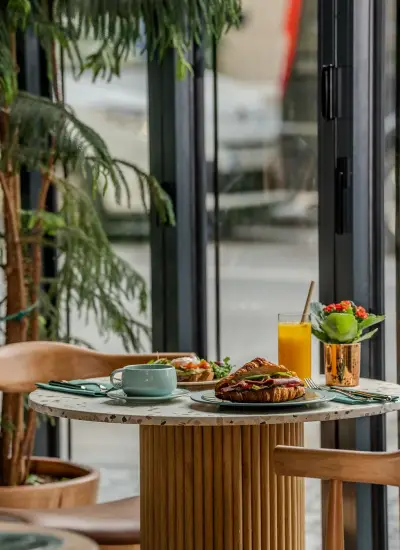 Yeşillikler arasında konumlanan Archer Bistro & Bar'da sıcak içecekler ve brunch tabağıyla dolu samimi bir masa.