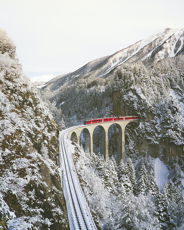 Karlı Alp manzarasında Landwasser Viadüğü üzerinde ilerleyen Bernina Express treni – İsviçre’nin panoramik kış yolculuğu