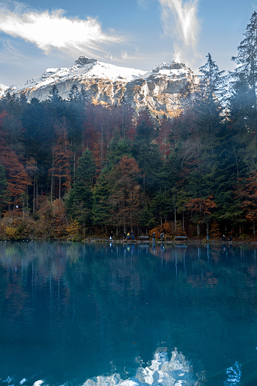 İsviçre’nin Blausee Gölü’nde sonbahar renkleri ve arka planda karlı dağ manzarası – doğa severler için huzurlu bir rota
