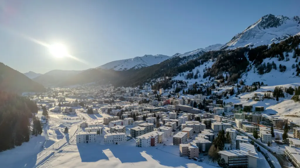 İsviçre’nin Graubünden kantonundaki Davos kasabasında kış güneşi altında parlayan karla kaplı manzara ve modern yerleşim alanları