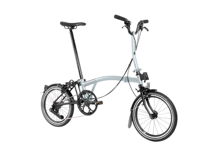 Beyaz arka planda sergilenen, açık gri metalik renkli ve kompakt tasarımıyla dikkat çeken Brompton P Line katlanır bisiklet, küçük tekerlekleri, kendine özgü katlanma mekanizması ve uzun sele borusuyla şehir içi ve toplu taşıma entegrasyonuna uygun ideal bir bisiklet modeli sunuyor.
