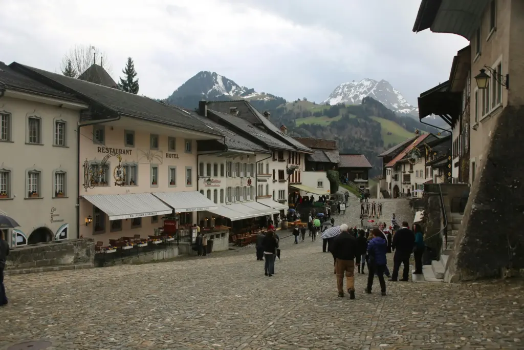 İsviçre’nin Fribourg kantonundaki Gruyères kasabasında Orta Çağ atmosferini yansıtan taş sokaklar, restoranlar ve arka planda dağ manzarası