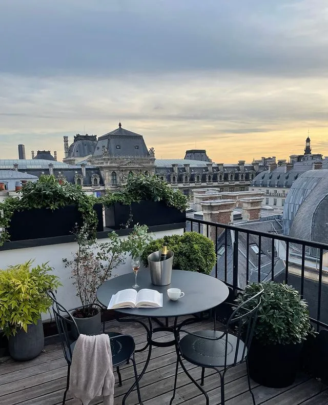 Paris'in meşhur tarihi binalarının ve göz alıcı çatı katlarının manzarasına sahip bir otel balkonunda, üzerinde açık bir kitap, şarap kadehi ve şampanya kovası bulunan zarif masa takımı, bu eşsiz şehirde Paris Gezi Rehberi'nin de bahsettiği gibi huzurlu anlar yaşamak için adeta bir film sahnesi sunuyor.