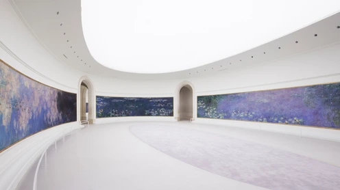 Musée de l'Orangerie'nin kavisli beyaz salonunda, Claude Monet'nin Nymphéas serisinden devasa, koyu mavi ve mor tonlarındaki nilüfer tabloları duvarları sararken, aydınlık ve ferah atmosfer ziyaretçilere eşsiz bir deneyim sunuyor.