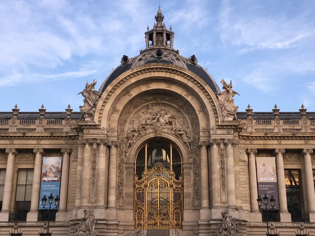 Petit Palais'nin altın rengi işlemeli kapısı, heykelleri ve kubbeli çatısıyla büyüleyici cephesi, Paris'in sanatla dolu, her köşesi bir film sahnesi gibi olan ikonik müzelerinden birini yansıtıyor.