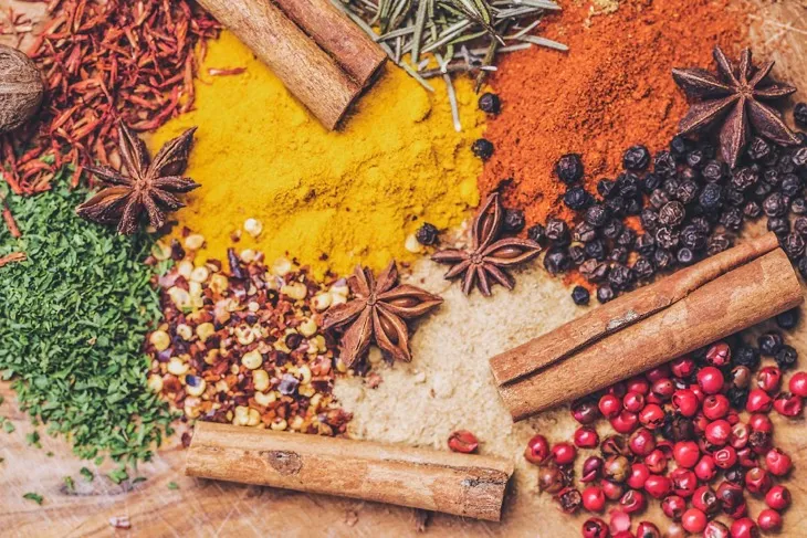 Renkli ve aromatik baharatlar: tarçın çubuğu, karabiber, yıldız anason ve çeşitli toz baharatlar.
