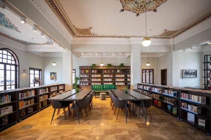 Kadıköy İskele Kütüphanesi'nin geleneksel tavan süslemeleriyle modern aydınlatmaları birleştiren geniş okuma salonunda, uzun çalışma masaları, bolca kitap barındıran raflar ve dinlenmek için yeşil koltuklar İstanbul'un en iyi kütüphanelerinden biri olan bu yeni nesil bilgi merkezini vurguluyor.