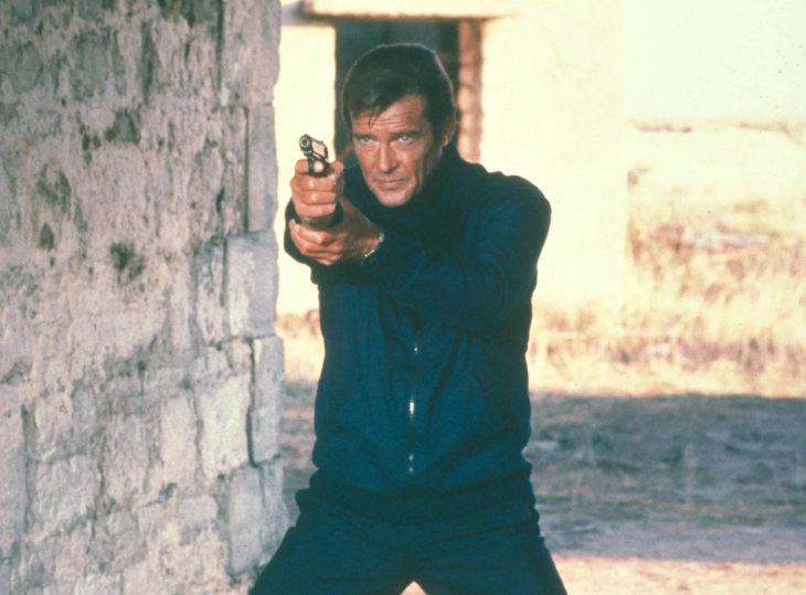 Koyu mavi fermuarlı ceketi ve pantolonuyla, Roger Moore'un ikonik James Bond karakteri olarak iki eliyle tabancasını kararlı bir ifadeyle doğrudan hedefe doğrulttuğu, arkasında kaba taş bir sütun ve açık renkli bir dış mekanın görüldüğü bu sahne, casus filmleri serisinin en iyi James Bond filmleri dönemlerinden birini yansıtıyor.