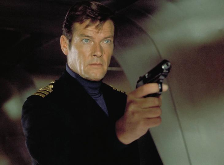 Roger Moore, ikonik James Bond karakterini canlandırırken, lacivert balıkçı yaka kazak ve omuzlarında altın apoletli koyu renk bir ceket giymiş, sağ elinde siyah bir tabanca tutarak doğrudan kameraya ciddi bir ifadeyle bakan, casus filmleri atmosferini yansıtan bir görsel.