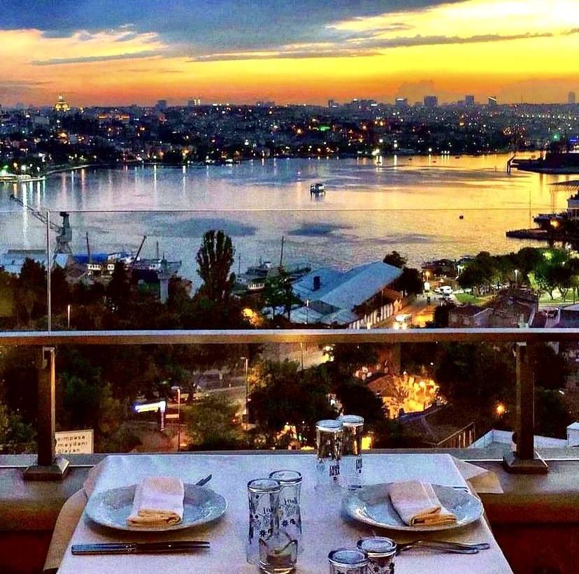 Gün batımının sıcak renkleriyle aydınlanan İstanbul semalarında, cam korkuluklu şık bir teraslı mekânda, iki kişilik özenle hazırlanmış masa eşliğinde Boğaz'ın ışıldayan eşsiz manzarası keyifli bir akşam yemeği vaat ediyor.
