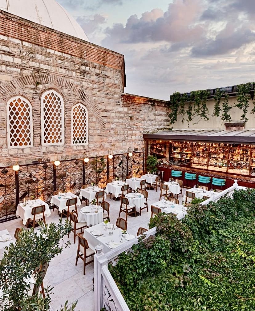Beyaz örtülü masaları, dolgun barı, kemerli pencereleri olan tarihi tuğla duvarları ve yemyeşil bitkileriyle zarif bir açık hava restoran terası, İstanbul’un en iyi teraslı mekanlarından biri olarak konuklarına keyifli bir akşam yemeği deneyimi sunuyor.