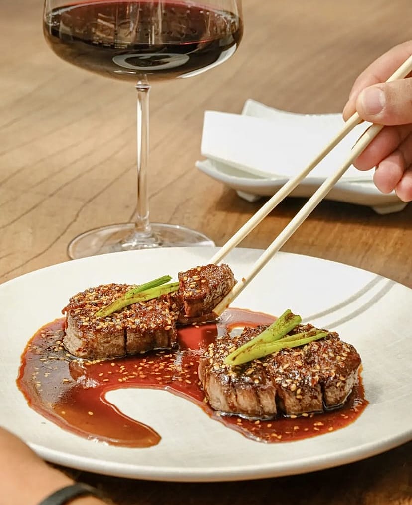 İstanbul'un gözde Uzak Doğu mutfağı restoranlarından birinde servis edilen, susam ve yeşil soğanla zenginleştirilmiş, etrafına özel sos gezdirilmiş iki parça dana etinden birinin zarif chopsticklerle tutulduğu, yanında bir kadeh kırmızı şarapla tamamlanan sunum.