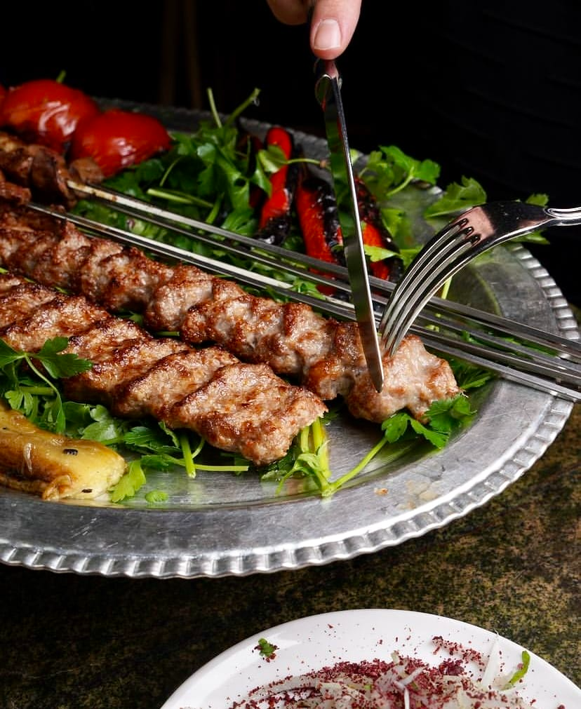 Müslüm Kebap’ta şişte pişirilmiş dana kebabı, taze yeşilliklerle sunum