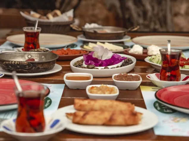 Rustik ahşap bir masada, bakır sahanda sunulan menemen, çeşit çeşit zeytinler, parlak reçeller, beyaz peynir ve tulum peyniri, taze salatalık ve domates dilimleri, kızarmış sigara börekleri ve ince belli bardaklarda demli çaylarla donatılmış, göz alıcı bir Türk kahvaltısı sofrası her lokmada ayrı bir keyif sunuyor.