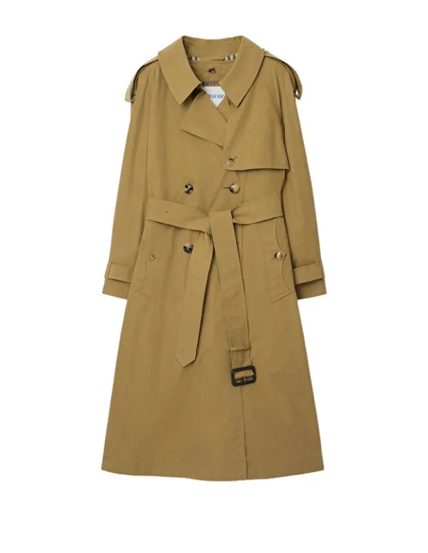 Beyaz fonda sergilenen, kemerli, kruvaze kesimli ve omuz apolet detaylarına sahip klasik kahverengi Burberry trençkot, mevsim geçişleri için kapsül gardırobun zamansız ve sofistike bir anahtar parçası olarak dikkat çekiyor.