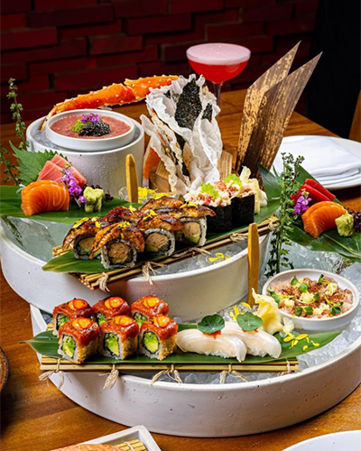 Bu görsel, İstanbul’un en popüler sushi restoranlarında sunulan zengin ve göz alıcı bir menüyü, buz üzerinde özenle sergilenmiş yılan balığı roll’ları, taze ton ve somon sashimi’ler, yengeç bacağı ve çeşitli nigirilerle modern Uzak Doğu mutfağının rafine lezzetini yansıtan bir şöleni detaylandırıyor.