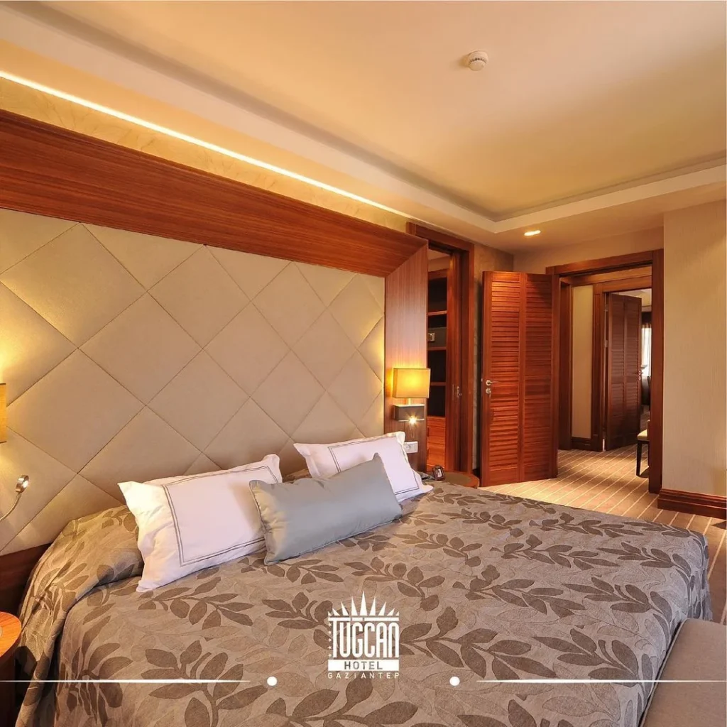 Gaziantep’te Tugcan Hotel’in sıcak ahşap detaylara sahip konforlu odası, modern dekorasyon ve rahat bir atmosfer sunuyor.