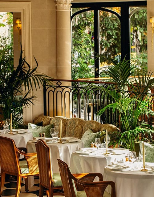 Paris'in kalbindeki Laurent restoranının klasik ve şık atmosferi, beyaz örtülü masaları, hasır sandalyeleri, yeşil yastıkları, gösterişli koltukları ve yemyeşil bitkileriyle zarafeti yansıtırken, dışarıya bakan kemerli pencereleri ferah bir Fransız mutfağı deneyimi sunar.