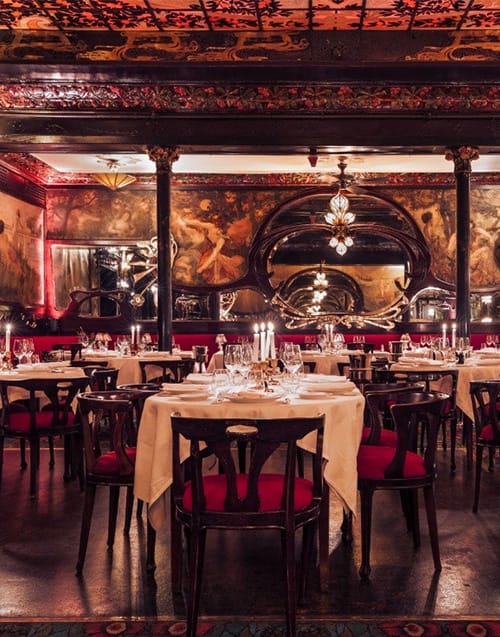 Bu lüks Paris restoranı, Art Nouveau tarzı detaylarla süslenmiş tavanı, duvarlardaki resimleri ve zarif aynalarıyla göz kamaştıran, kırmızı minderli sandalyeler ve şamdanlarla donatılmış masalarıyla loş ve romantik bir yemek ortamı sunuyor.