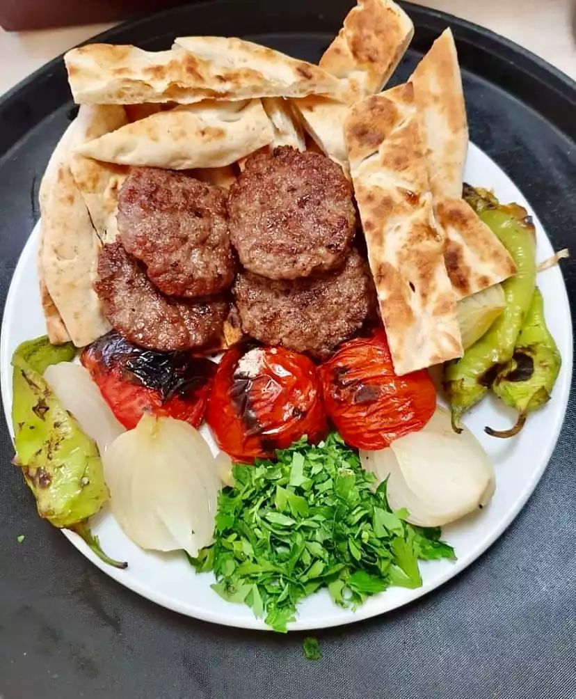 Antalya usulü şiş-piyaz geleneğini yaşatan bir mekânda, bol ızgara köfte, çıtır tırnak pide, közlenmiş domates, biber ve soğan ile taze maydanozun iştah açıcı bir uyumla servis edildiği zengin bir ana yemek tabağı.