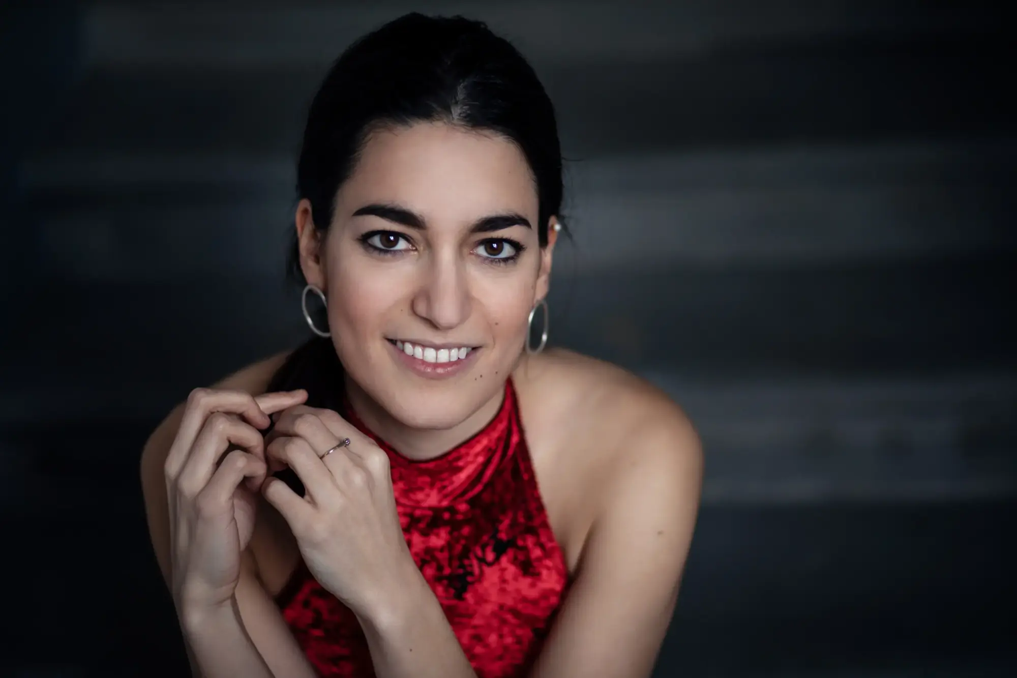 Koyu arka plan önünde kırmızı kadife elbiseli genç kadın sanatçı portresi, festival konseri tanıtım görseli.