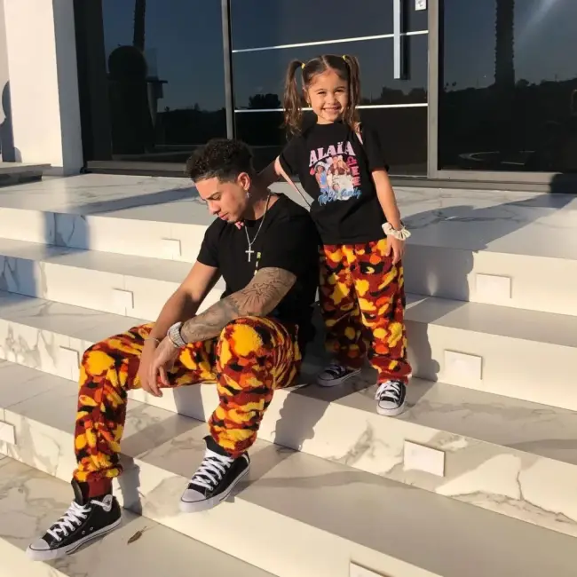 Austin McBroom ve kızının, benzer desenli alt giysilerle uyumlu bir sokak stili sergiledikleri, dışarıda merdivenlerde oturdukları bir fotoğraf.
