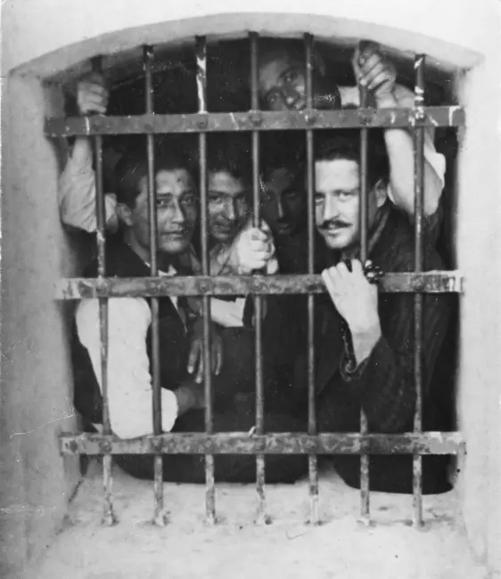 Nazım Hikmet ve birkaç mahkum, cezaevi parmaklıklarının ardında birlikte poz veriyor.