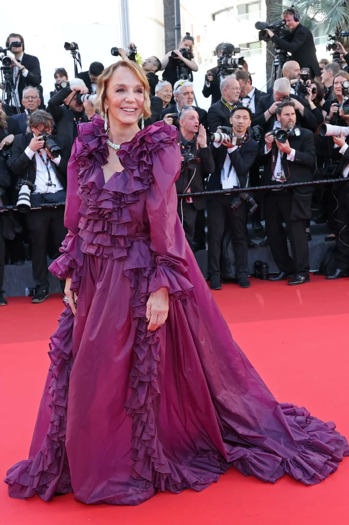 Cannes Film Festivali'nin 77'ncisinde kırmızı halı üzerinde yürüyen Philippine Leroy-Beaulieu, omuzdan etek ucuna dek uzanan volanlı detaylara sahip, canlı mor tonlarındaki göz alıcı haute couture elbisesiyle gülümsüyor.