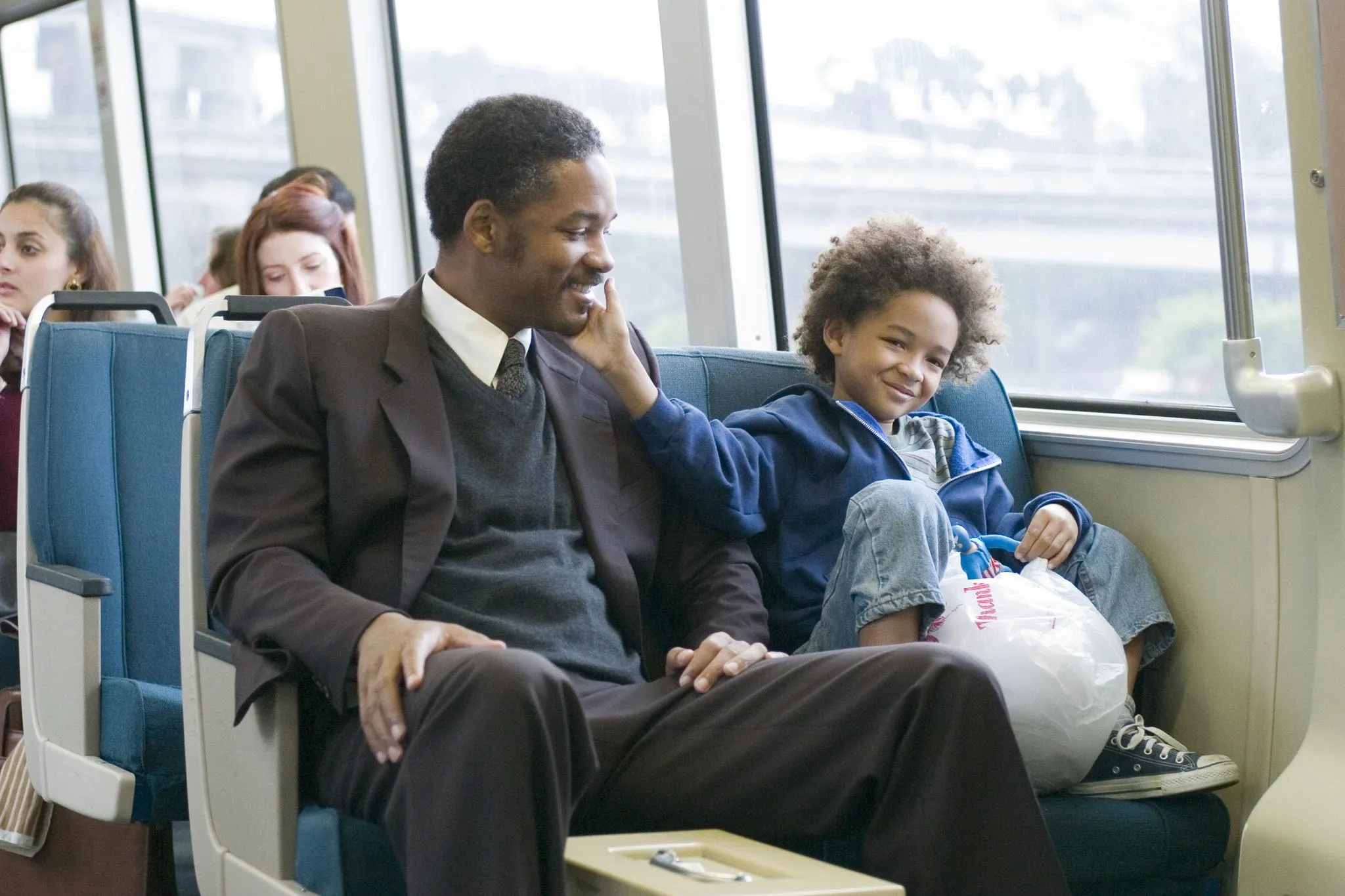 The Pursuit of Happyness filminde Chris Gardner (Will Smith) ve oğlu (Jaden Smith), trende keyifli bir an paylaşırken.