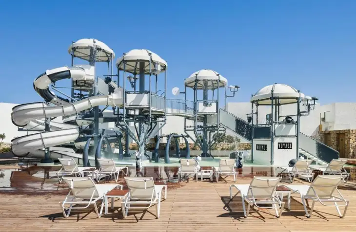 Marka Adı: Voyage
Ürün Adı: Voyage Çocuk Aquapark Havuzu
Ürün Cinsiyeti: Çocuk
Ürün Tipi: Aquapark Havuzu
Ürün Sezonsallığı: Yazlık
Ürün Çeşidi: Açık Hava Su Eğlence Tesisi
Ürün Özellikleri: Beyaz ve gri tonlarında tasarlanmış bu çocuk aquaparkı, modern ve eğlenceli bir görünüm sunar. Farklı yüksekliklerde ve kıvrımlarda çok sayıda su kaydırağı ile çocuklara çeşitli eğlence seçenekleri sunar. Güvenli kullanım için sığ bir havuz alanına ve su püskürtme özelliklerine sahiptir. Metal ve dayanıklı kompozit malzemelerden inşa edilmiş ana yapı, sağlamlık ve uzun ömürlü kullanım vaat eder. Aquaparkın etrafı, dinlenme ve güneşlenme için düzenli olarak yerleştirilmiş beyaz şezlonglar ve ahşap zeminle çevrilidir, bu da ebeveynlerin çocuklarını rahatça izlemesini sağlar. Tesisin marka kimliğini yansıtan Voyage logoları aquaparkın tasarımına entegre edilmiştir.
Öne Çıkan Detaylar:
- Birden fazla farklı su kaydırağı ve su püskürtme sistemleri
- Güvenli ve çocuk dostu sığ havuz alanı
- Ebeveynler için konforlu şezlonglara sahip geniş ahşap zeminli dinlenme alanı
Kimler Kullanıyor?: Ailelerin çocuklarıyla birlikte güvenli ve eğlenceli bir tatil geçirmek isteyenler, su aktivitelerini ve oyun parklarını seven küçük misafirler ile onların keyifli anlarını izlerken dinlenmeyi tercih eden ebeveynler bu tesisi kullanabilir. Her yaştan çocuğun fiziksel gelişimine uygun, coşkulu ve neşeli bir ortam arayan herkes için idealdir.