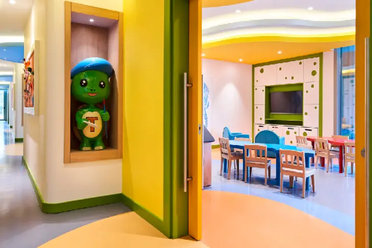 Marka Adı: Tugi Kids World
Ürün Adı: Tugi Kids World Çocuk Mini Kulübü
Ürün Cinsiyeti: Çocuk
Ürün Tipi: Çocuk Mini Kulübü
Ürün Sezonsallığı: Belirtilmemiş
Ürün Çeşidi: Otel İçi Çocuk Eğlence Alanı
Ürün Özellikleri: Bu çocuk mini kulübü, canlı ve neşeli renk paletiyle çocuklara ilham veren bir ortam sunar. Sarı, yeşil, turuncu ve mavi tonlarının ağırlıklı olduğu duvarlar, tavan ve zemin dikkat çekicidir. İçerisinde çocuk boyutlarında mavi, kırmızı ve doğal ahşap tonlarında masa ve sandalyeler bulunur. Eğlence ve eğitim için duvara monte edilmiş bir TV ekranı ve altında depolama dolapları mevcuttur. Mini kulübün girişinde, markanın sevimli kaplumbağa maskotu Tugi'nin heykeli, çocukları karşılayarak alana neşeli bir hava katmaktadır. Modern ve fonksiyonel tasarımıyla çocukların güvenli ve keyifli vakit geçirmesi için idealdir.
Öne Çıkan Detaylar:
- Canlı ve neşeli renklerle tasarlanmış iç mekan
- Çocuklara özel boyutlarda masa ve sandalyeler
- Girişte yer alan Tugi kaplumbağa maskotu ve etkileşimli TV alanı
Kimler Kullanıyor?: Ailece tatil yapan, çocukları için güvenli, eğlenceli ve eğitici bir ortam arayan ebeveynler ile yaratıcı ve sosyal aktivitelere katılmaktan hoşlanan her yaştan çocuklar için idealdir. Renkli ve ilham verici alanlarda keyifli zaman geçirmeyi seven minik misafirler, bu özel kulüpte yeni arkadaşlıklar kurup unutulmaz anılar biriktirebilirler.