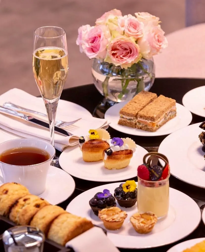 Raffles Istanbul’da afternoon tea sunumu – çay, şampanya kadehi, mini sandviçler, scone’lar ve çiçek süslemeli masa