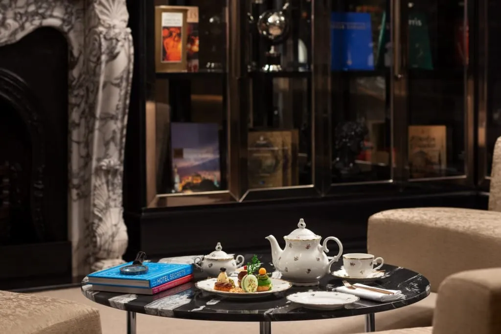 Sanasaryan Han The Library salonunda antika kitaplarla çevrili masa üzerinde zarif çay takımı ve atıştırmalıklar – Afternoon Tea İstanbul