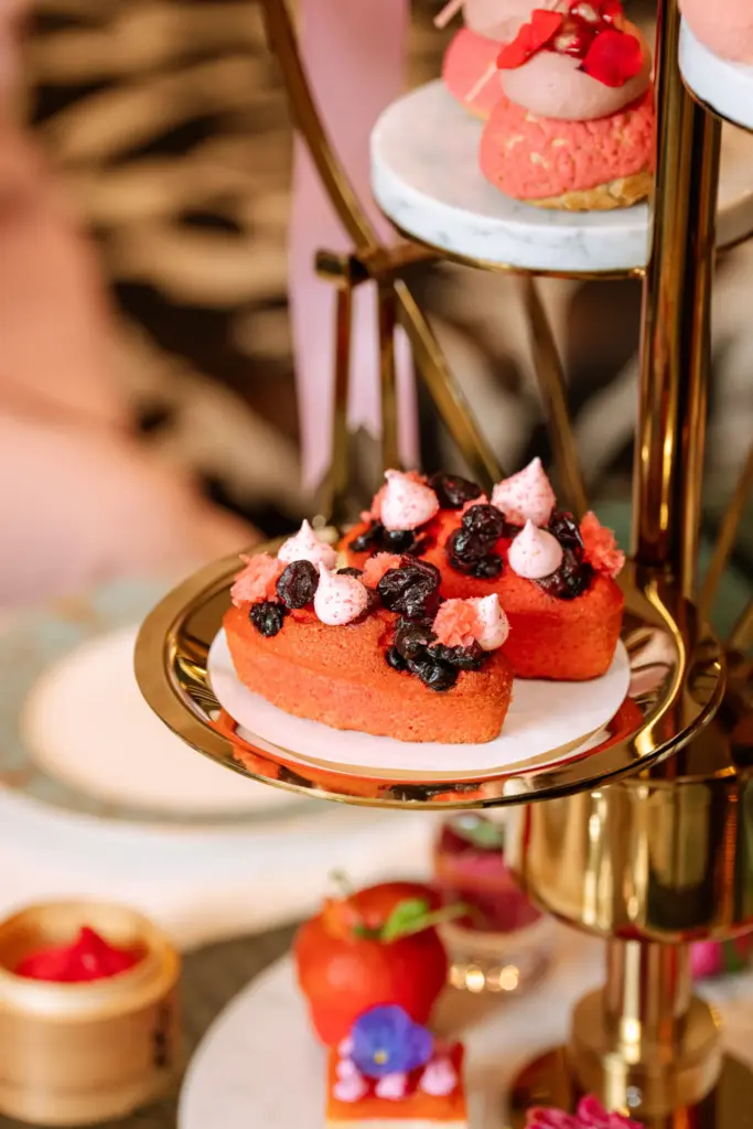 Shangri-La Bosphorus Pinktober Afternoon Tea menüsünden pembe meyveli mini pastalar ve yenilebilir çiçek süslemeleriyle zarif sunum
