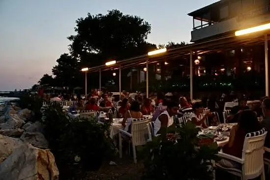 Edremit'in en iyi restoranları rehberinde yer alan deniz kıyısındaki restoranda canlı ve samimi akşam yemeği atmosferi.