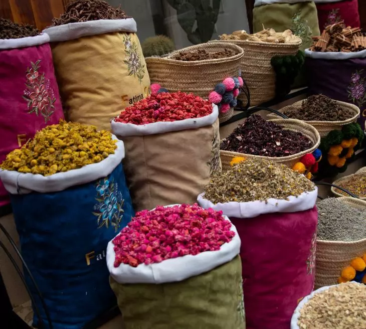 Ortakent Pazarı'nda rengarenk işlemeli kumaş çuvallar ve hasır sepetler içinde, kurutulmuş gül yapraklarından sarı çiçeklere, aromatik bitki çaylarına ve çeşitli baharatlara uzanan zengin ürünler canlı ve düzenli bir şekilde sergilenerek müşterileri bekliyor.