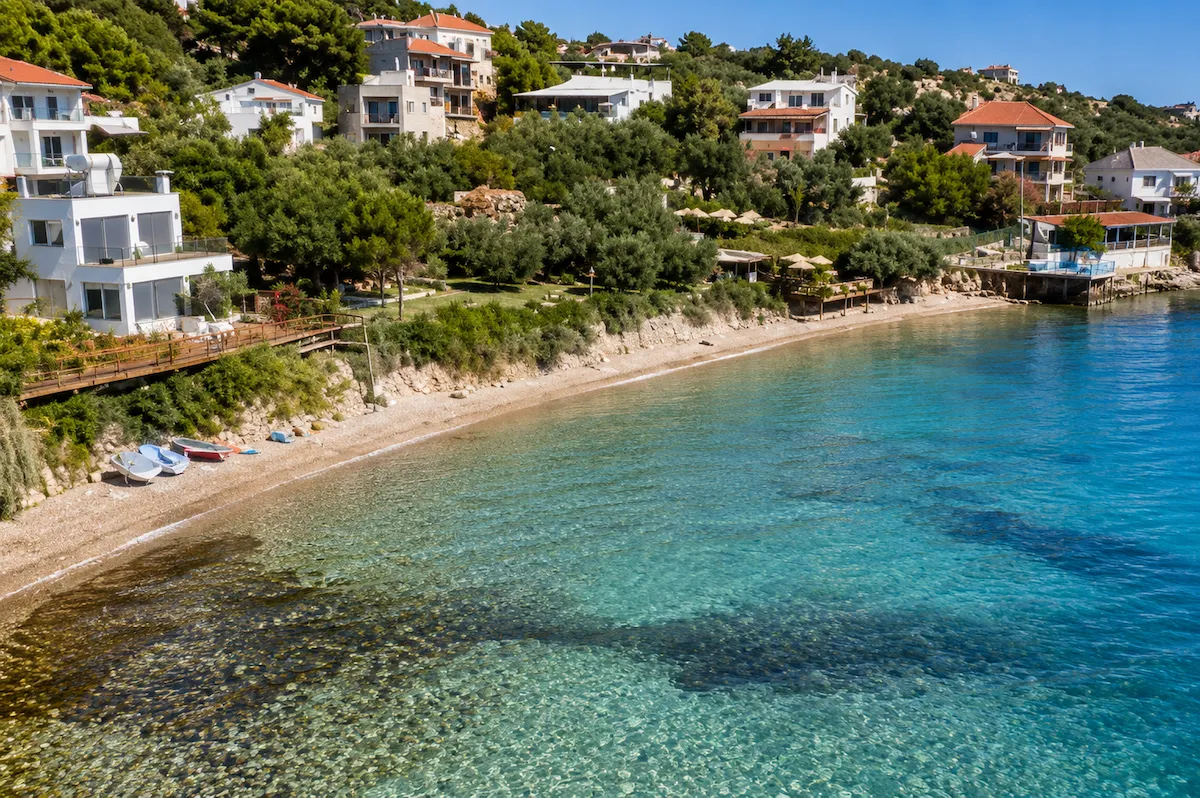 İzmir'in Karaburun ilçesindeki Boyabağı Koyu'nda, yamaçtaki yeşil ağaçlar ve beyaz evlerin çevrelediği berrak turkuaz sulara sahip çakıllı plaj, kıyıya çekilmiş küçük teknelerle sakin bir Akdeniz atmosferi sunuyor.