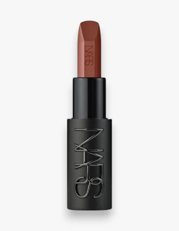 NARS markasının popüler Explicit Lipstick serisinden, sıcak bir nude kahverengi tona sahip Body Heat isimli ruj, kısmen açılmış koyu renkli, üzerinde belirgin NARS logosu bulunan mat siyah ambalajında, özenle sergilenmiş bir şekilde beyaz fonda dikey durmaktadır.