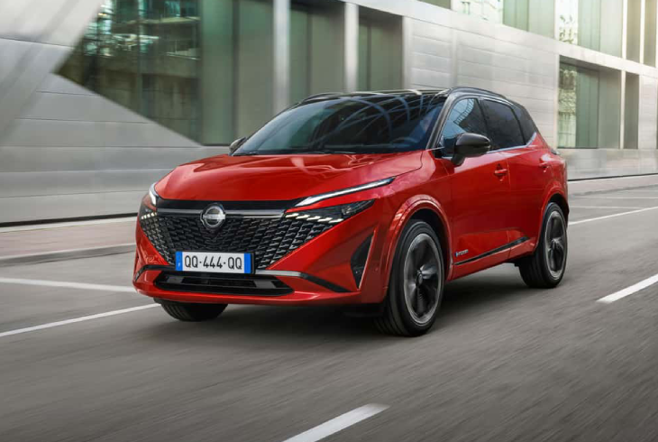 Kırmızı Nissan Qashqai SUV, modern şehir sokaklarında sürüş halinde dinamik tasarımıyla öne çıkıyor.