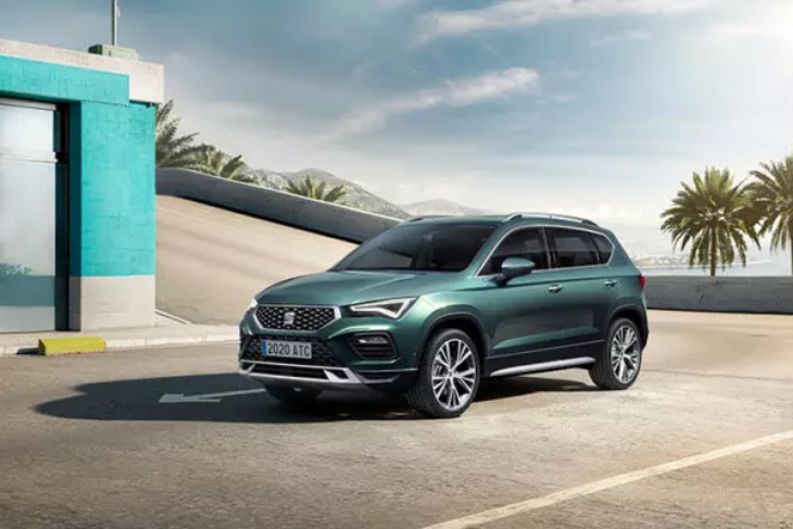 Yeşil Seat Ateca SUV, açık hava ve palmiyeli şehir ortamında modern tasarımıyla park halinde sergileniyor.