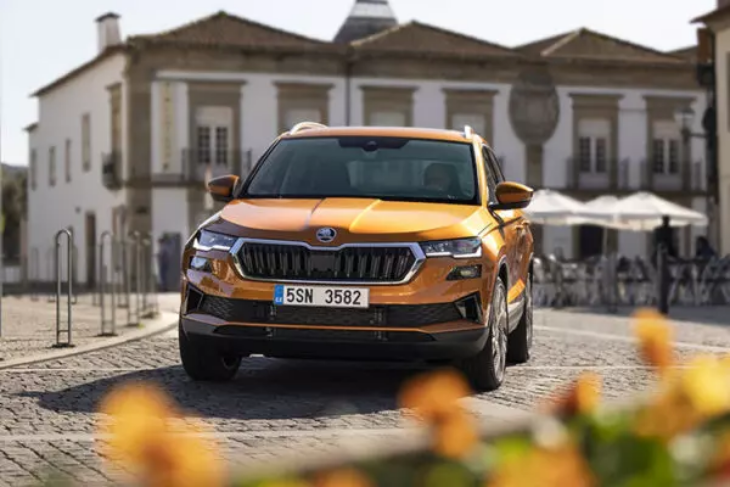 Turuncu Skoda Karoq SUV, tarihi meydan atmosferinde önden görünümüyle şehir yaşamına uyumlu tasarımıyla öne çıkıyor.