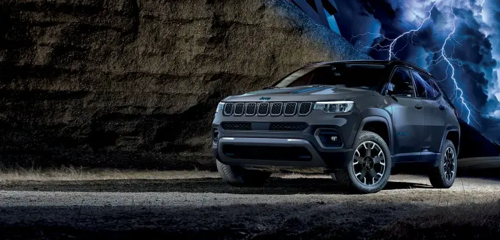 Gri Jeep Compass SUV, kayalık arazi ve fırtınalı gökyüzü fonunda güçlü ve dayanıklı tasarımıyla öne çıkıyor.